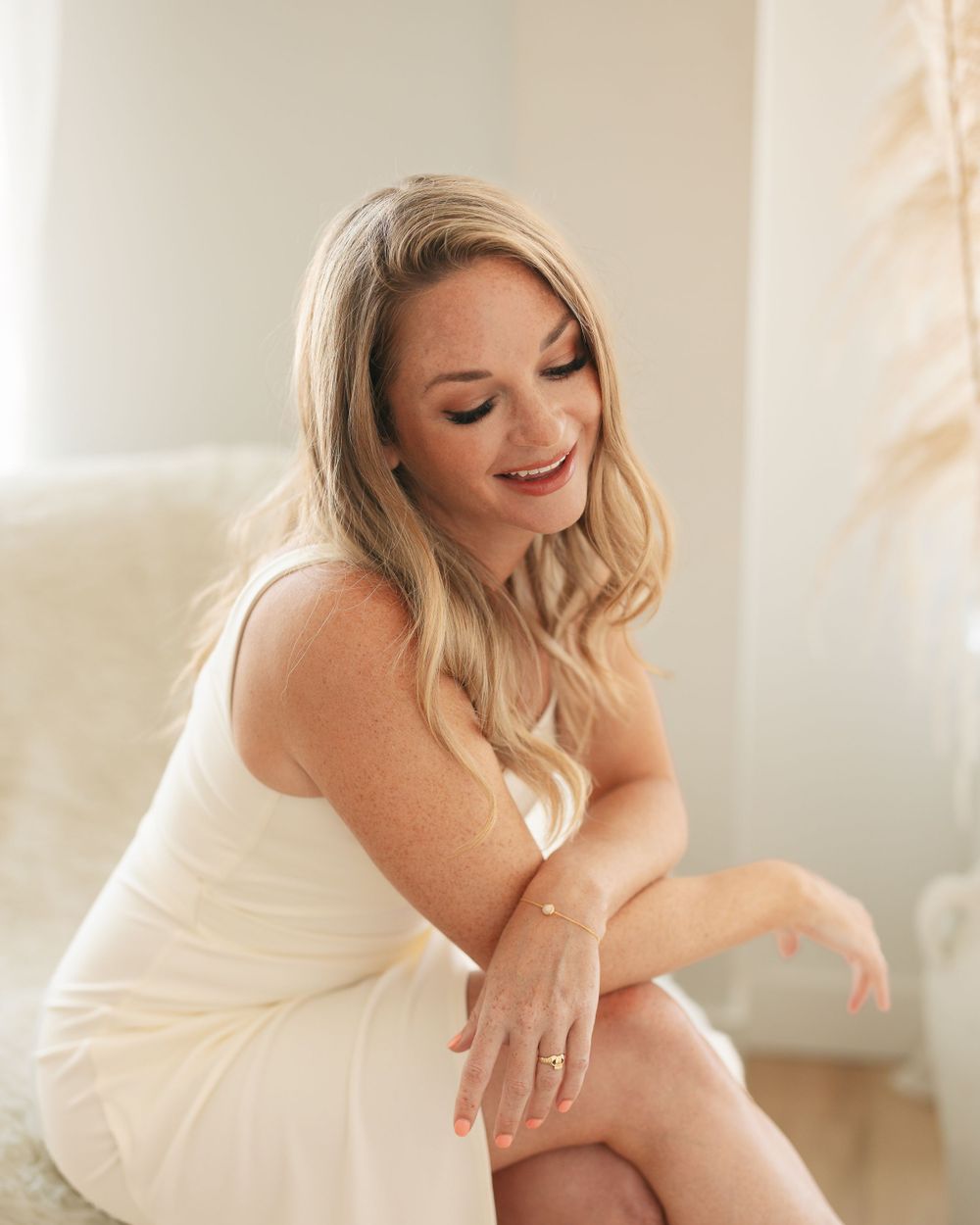Casual portrait in cream dress showing natural smile in bright indoor setting.