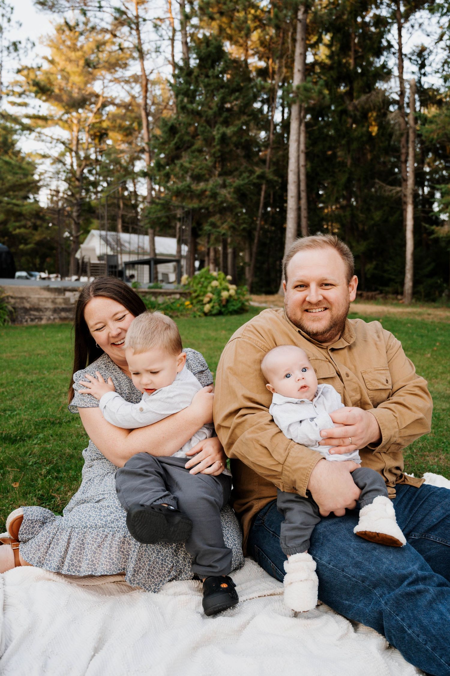 A family sitting on a blanket for outdoor portraits in their backyard.