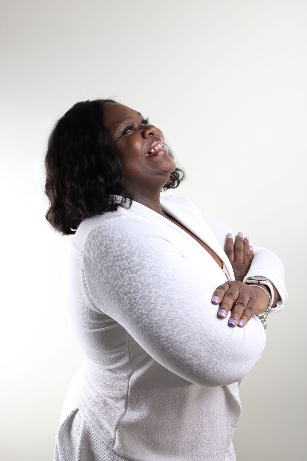 Studio portrait of person in white sweater laughing joyfully against light background.