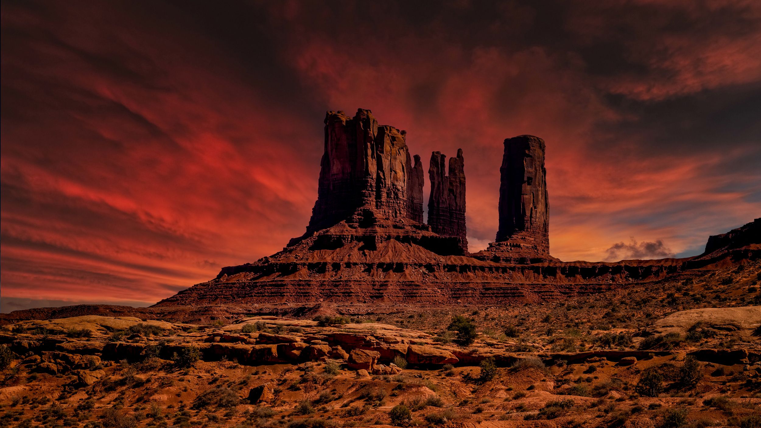Dramatic red sunset sky over Monument Valley's iconic sandstone buttes in the desert landscape.