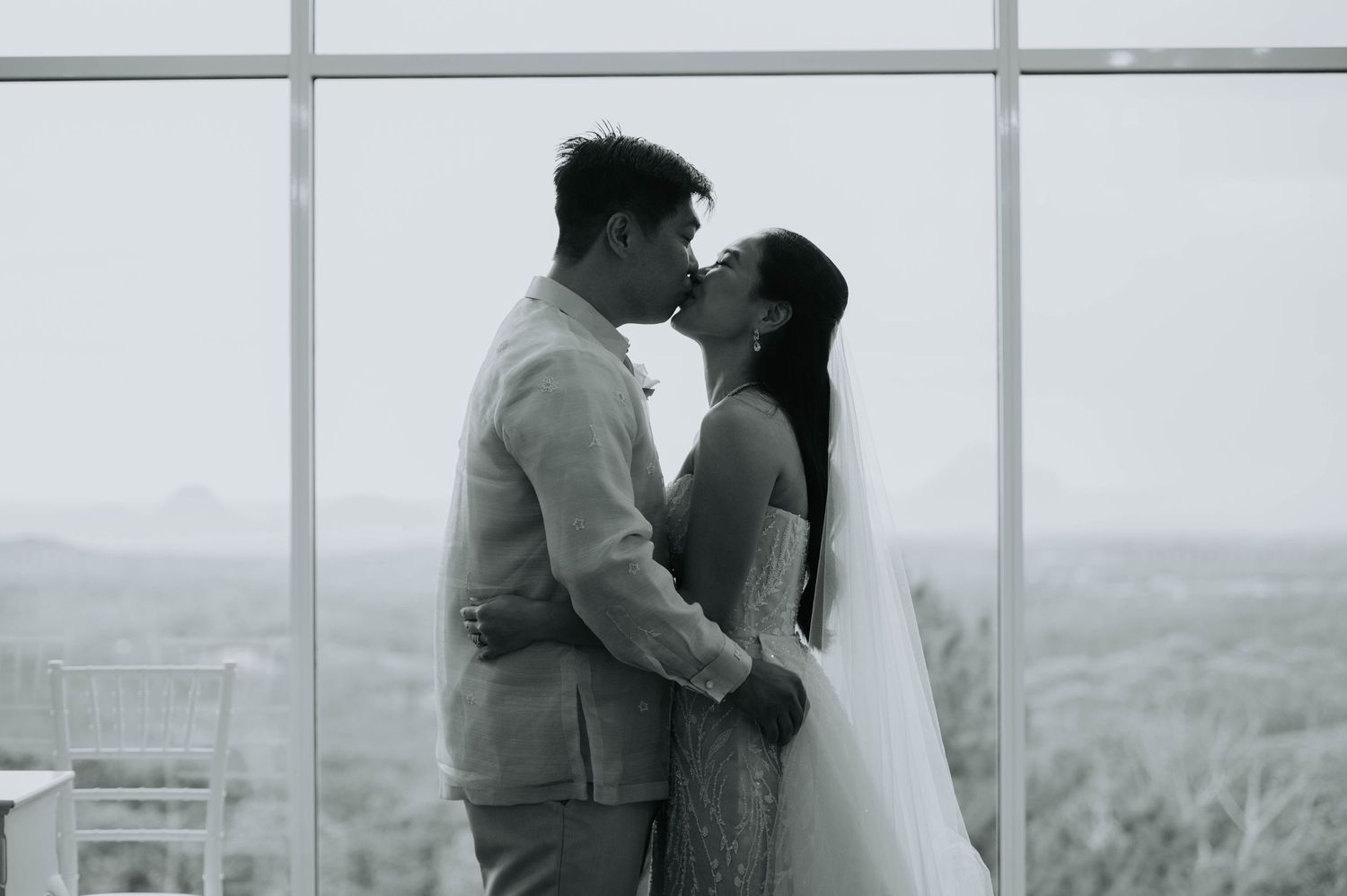 A romantic silhouette of a couple embracing by large windows with a scenic backdrop.
