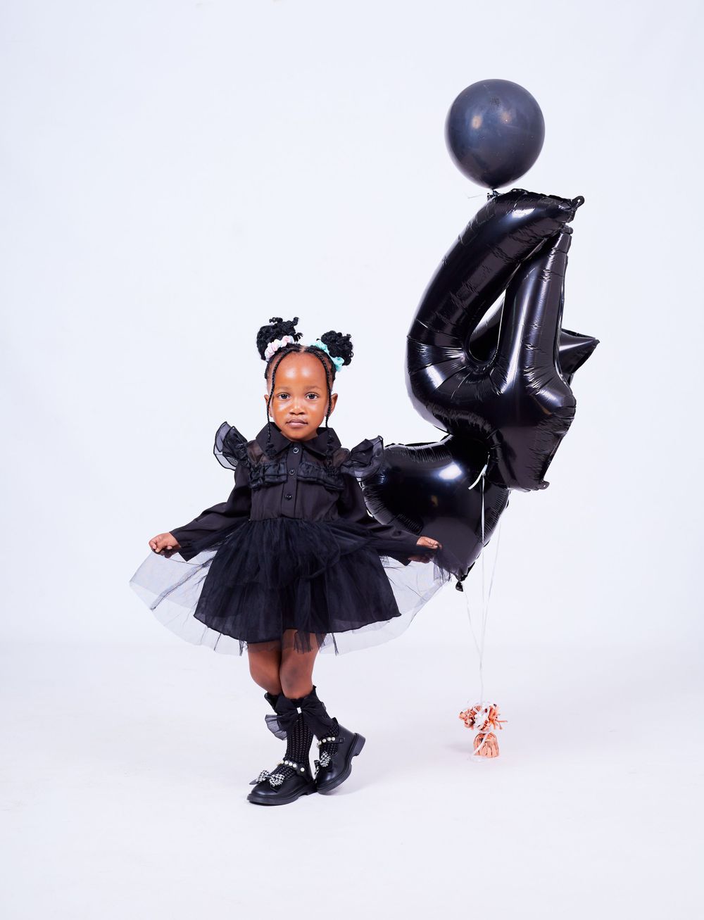 Child twirls in black tulle dress with matching black number balloons and decorations.