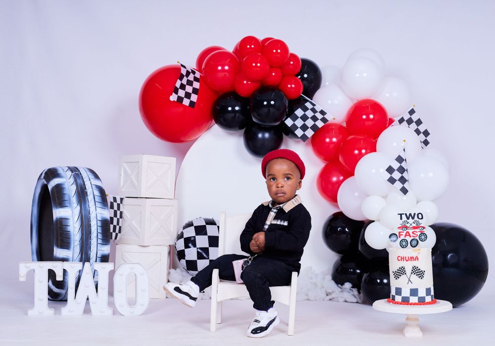 Race car themed birthday setup with red, black and white balloons and checkered flags.