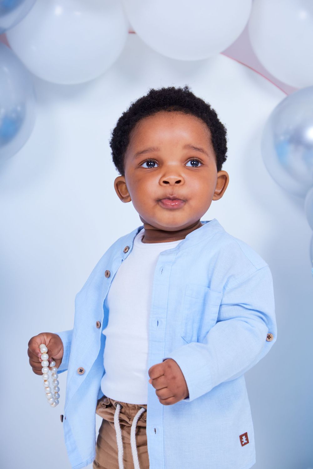 Studio photoshoot setup with blue and white balloon decorations and soft lighting.