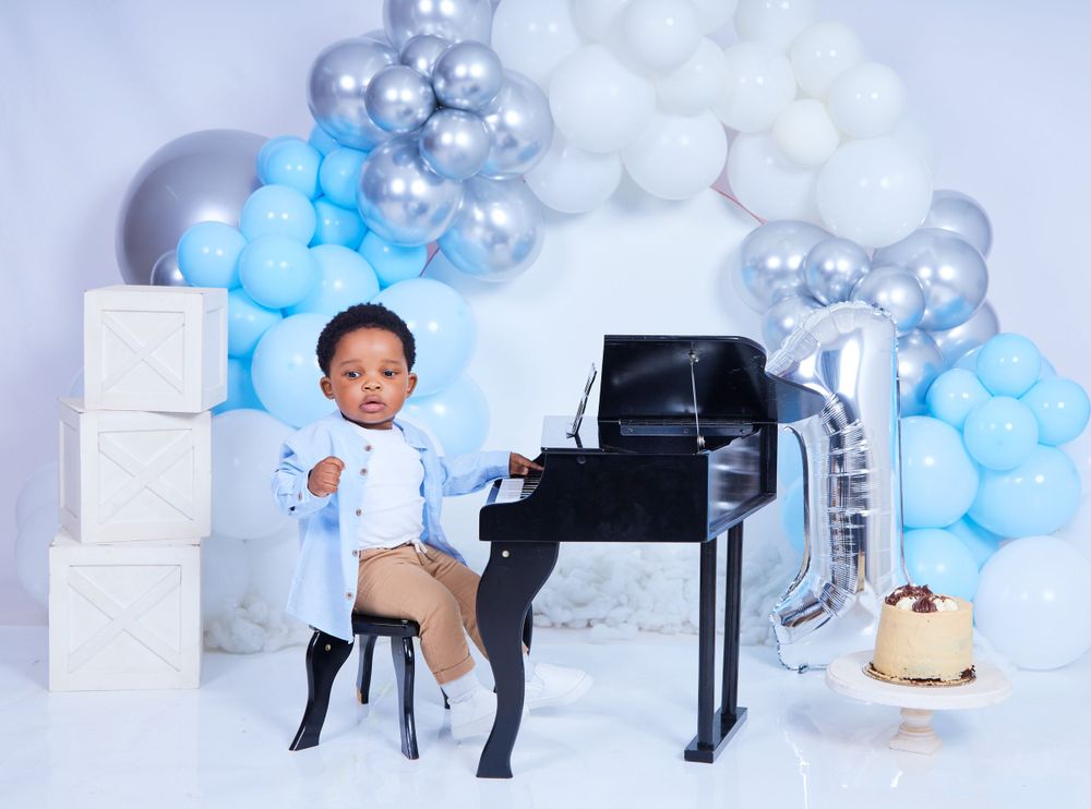 Professional photo studio with blue and silver balloon arch and white furniture.