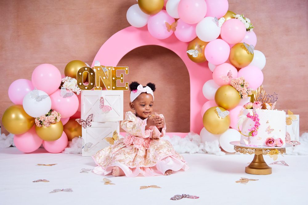 Birthday party setup with pink balloons, gold accents, and decorative cake display.