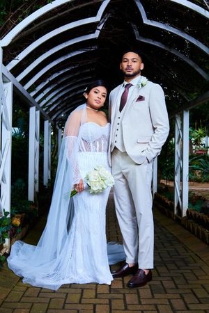 Romantic wedding photos taken under white garden archway with brick path.