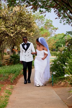 Wedding couple strolls together on a scenic garden pathway during their special day.