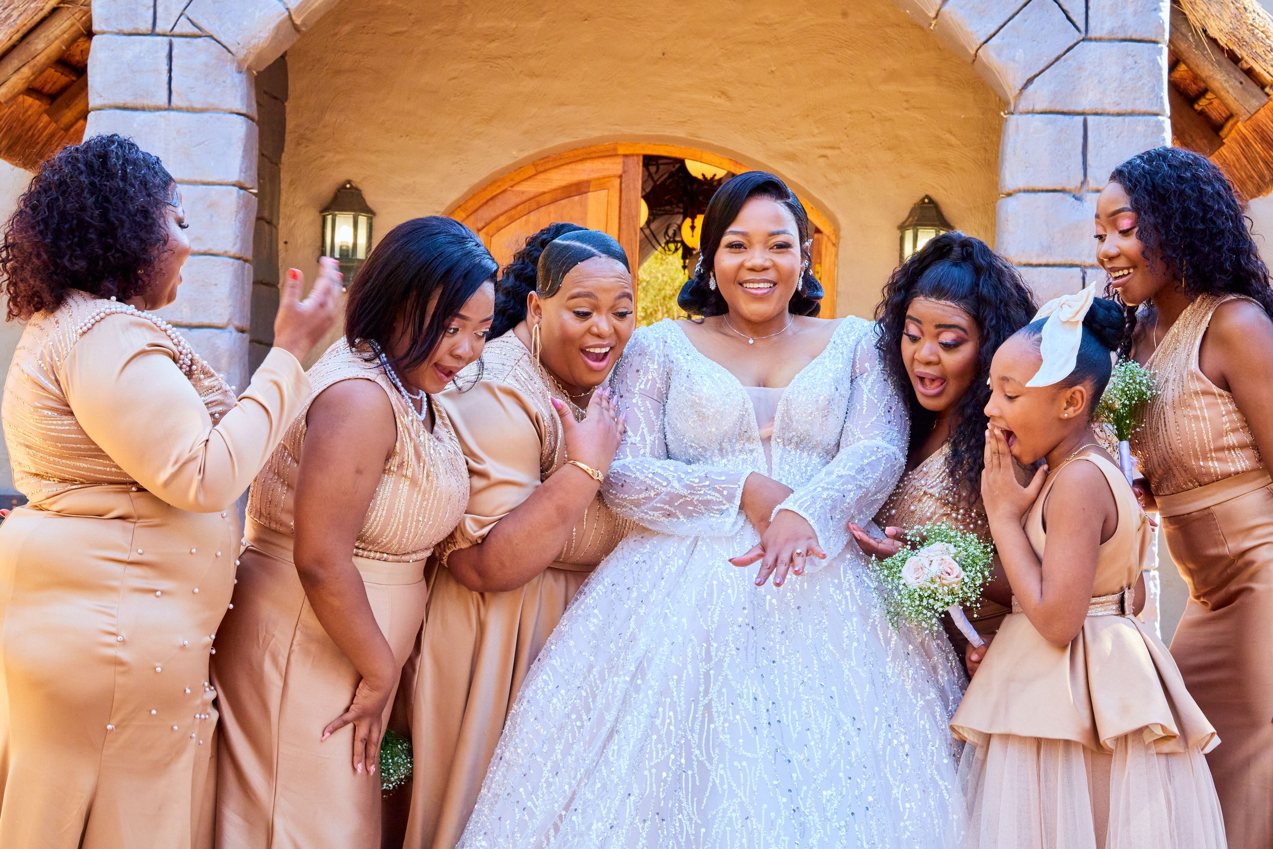 Wedding party in champagne and white attire posing together.