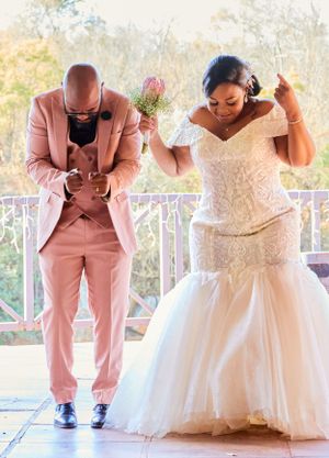 Wedding party in pink suits and white dresses striking fun poses.