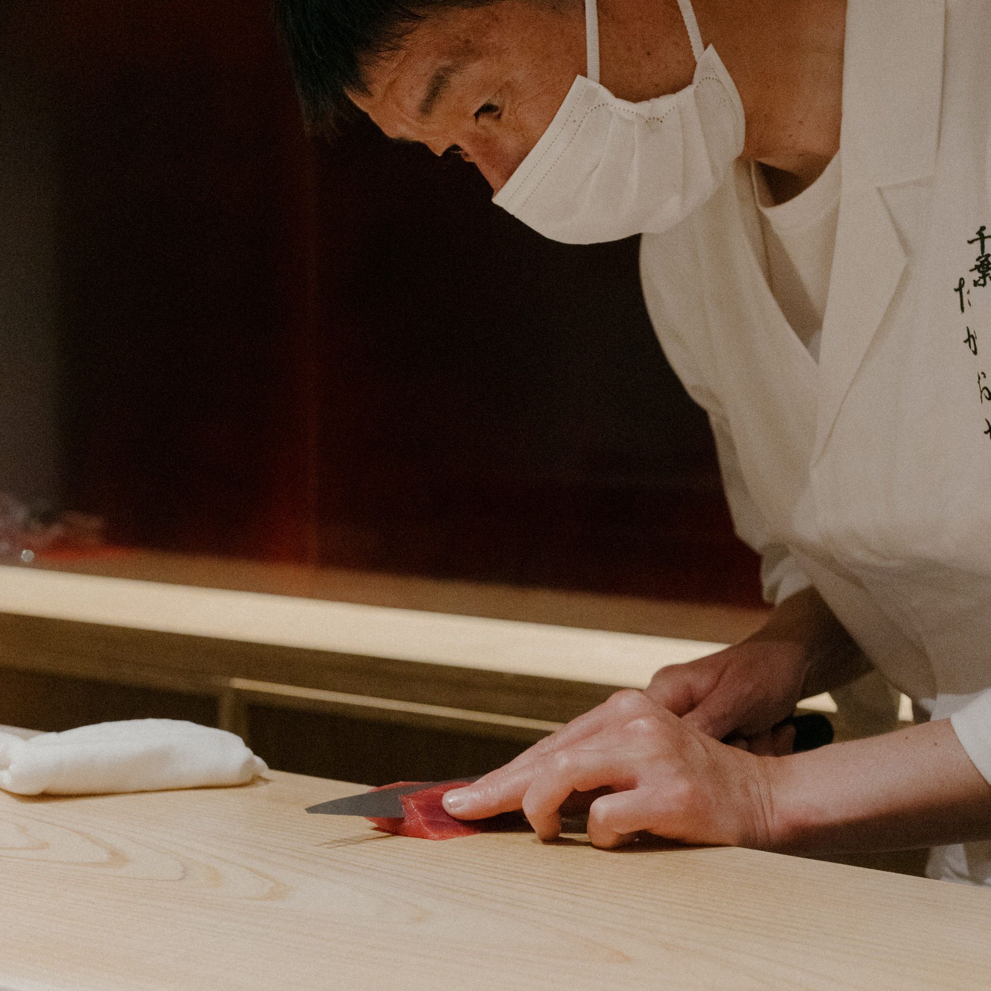 A chef preparing ingredients on a wooden cutting board in a professional kitchen.