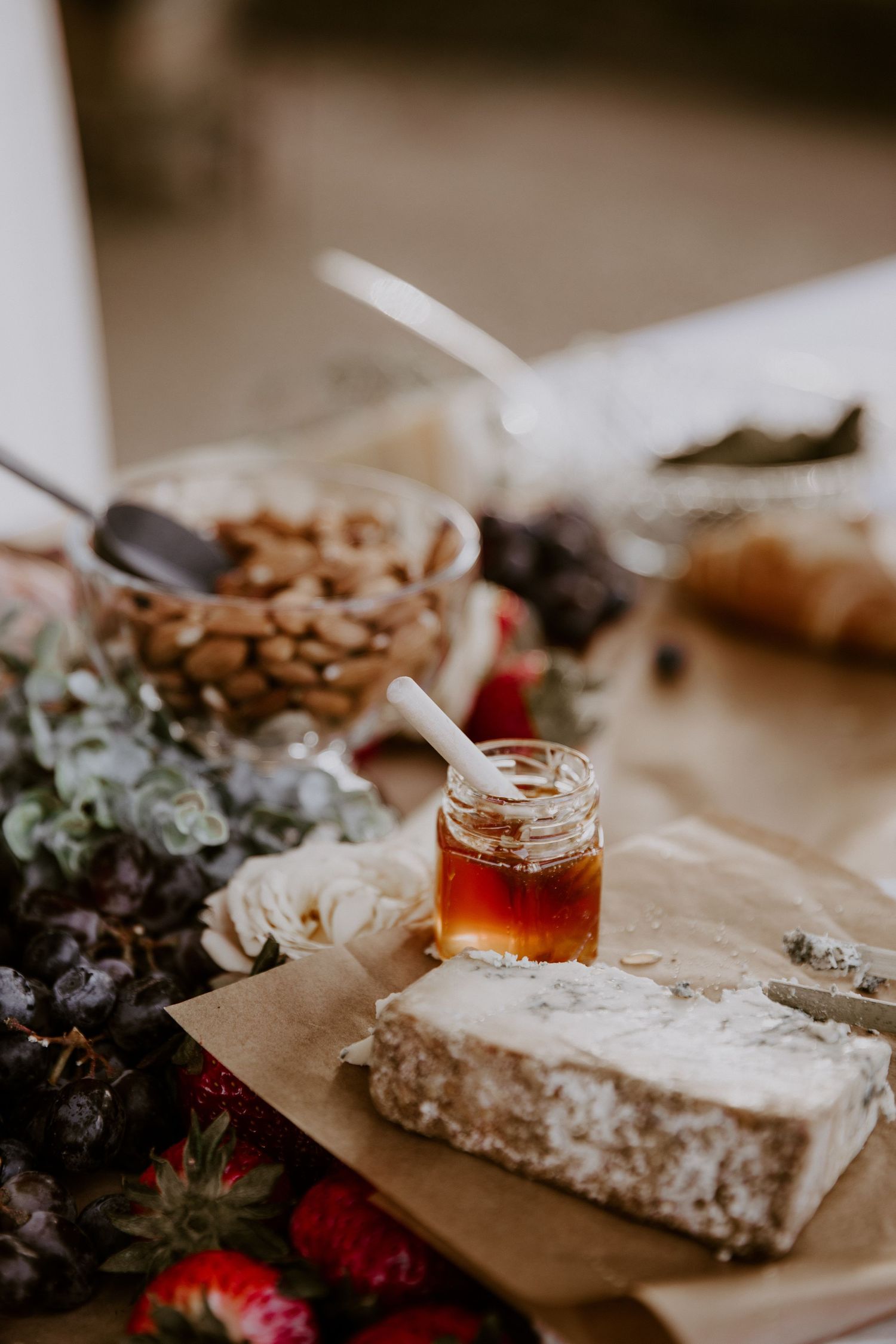 Artisanal cheese board with honey and fresh berries on parchment paper.