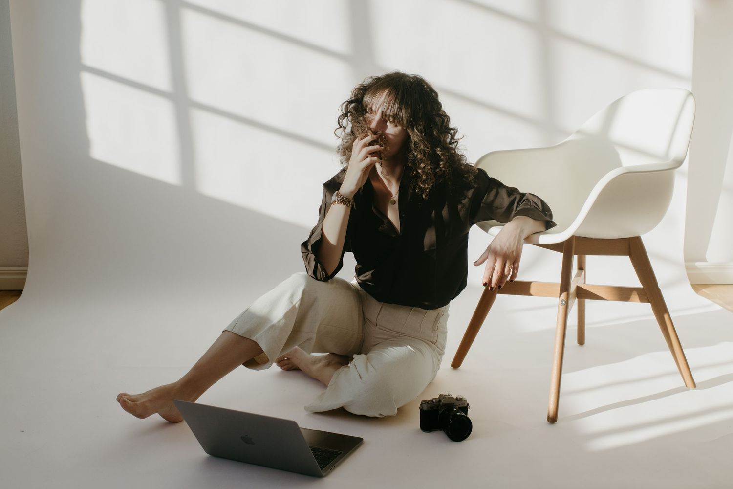 event photographer in stockholm sitting in a studio leaning into a chair with white background behind her