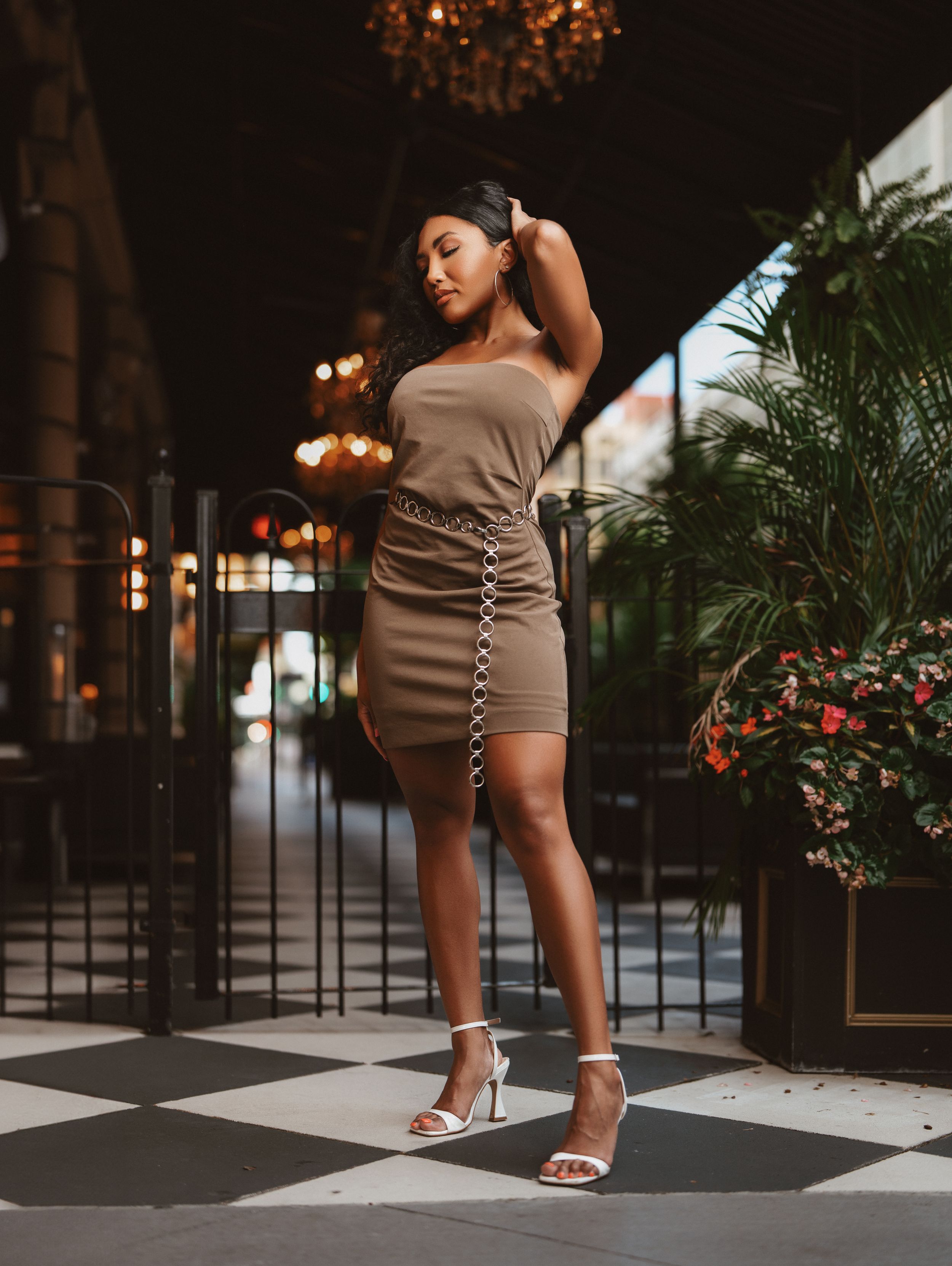 Elegant woman in a tan strapless mini dress posing on a checkered floor at night in Cincinnati