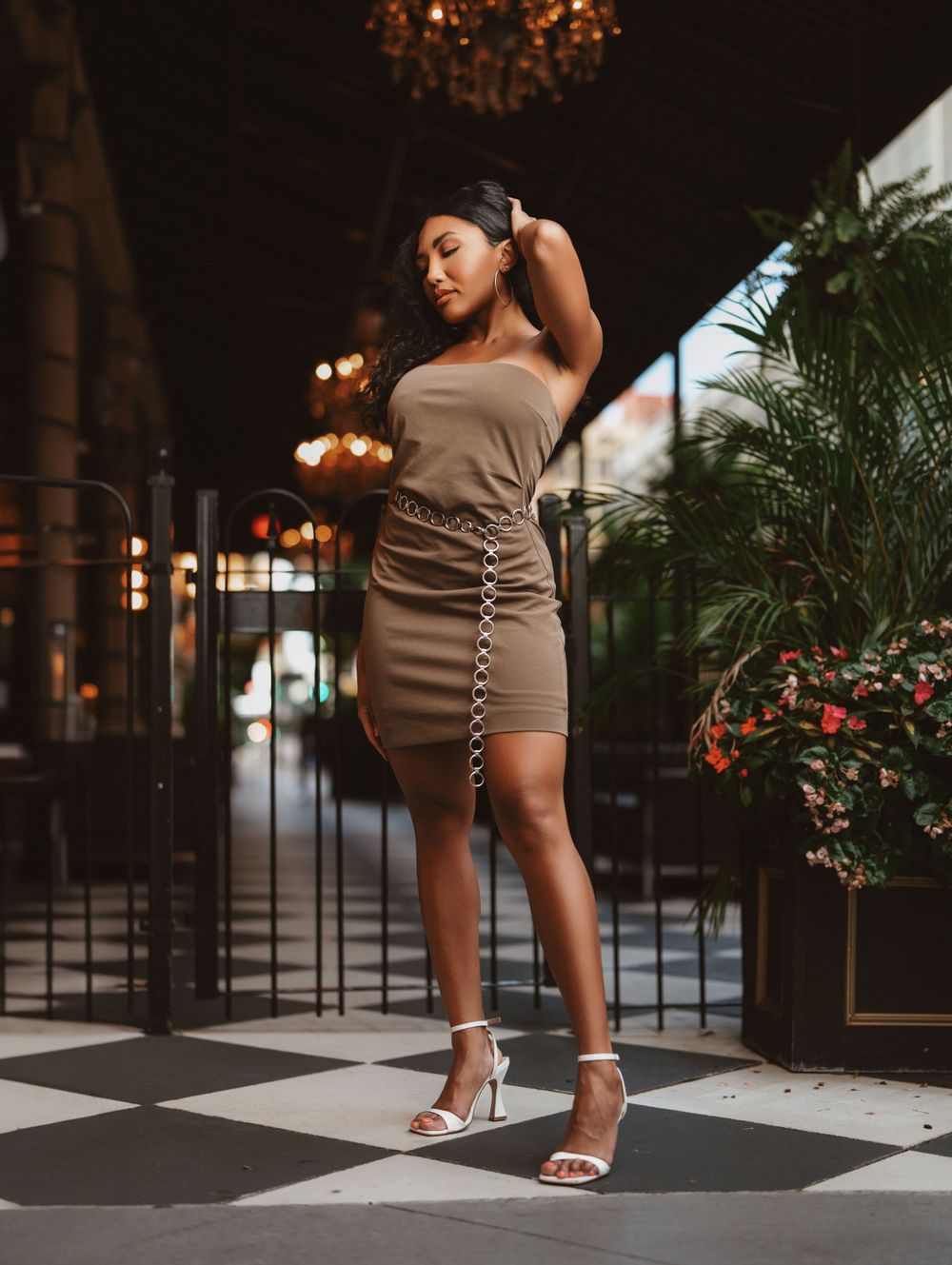 Elegant woman in a tan strapless mini dress posing on a checkered floor at night in Cincinnati