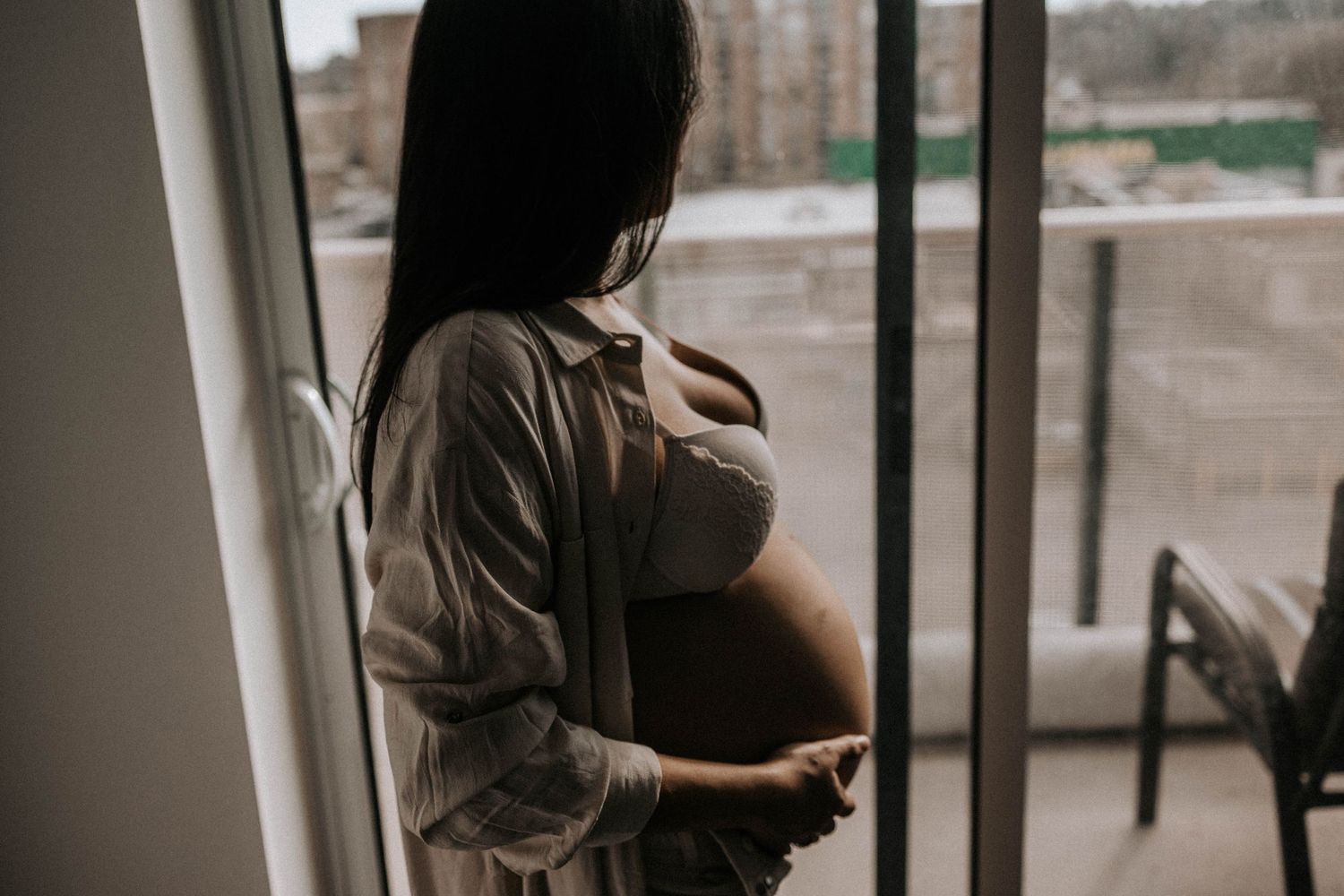 Pregnant woman looking at her windown, holding her belly, in York, Toronto