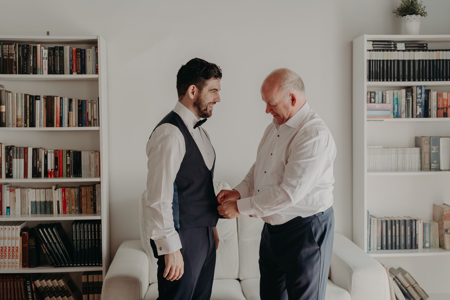 Getting ready moment in library setting with white bookshelves and formal attire.