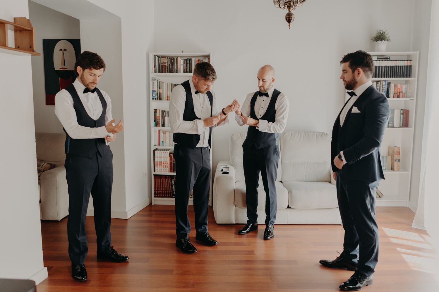 Groomsmen in formal attire gather in a bright indoor space before the ceremony.