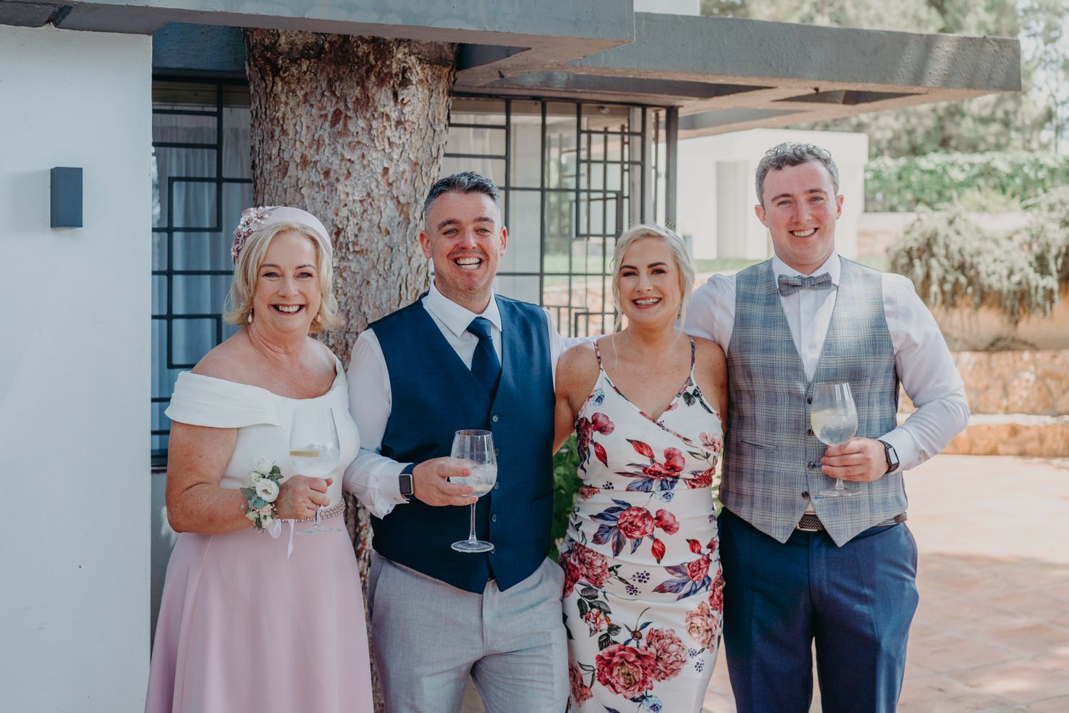 Small group of wedding guests enjoying drinks at outdoor celebration.