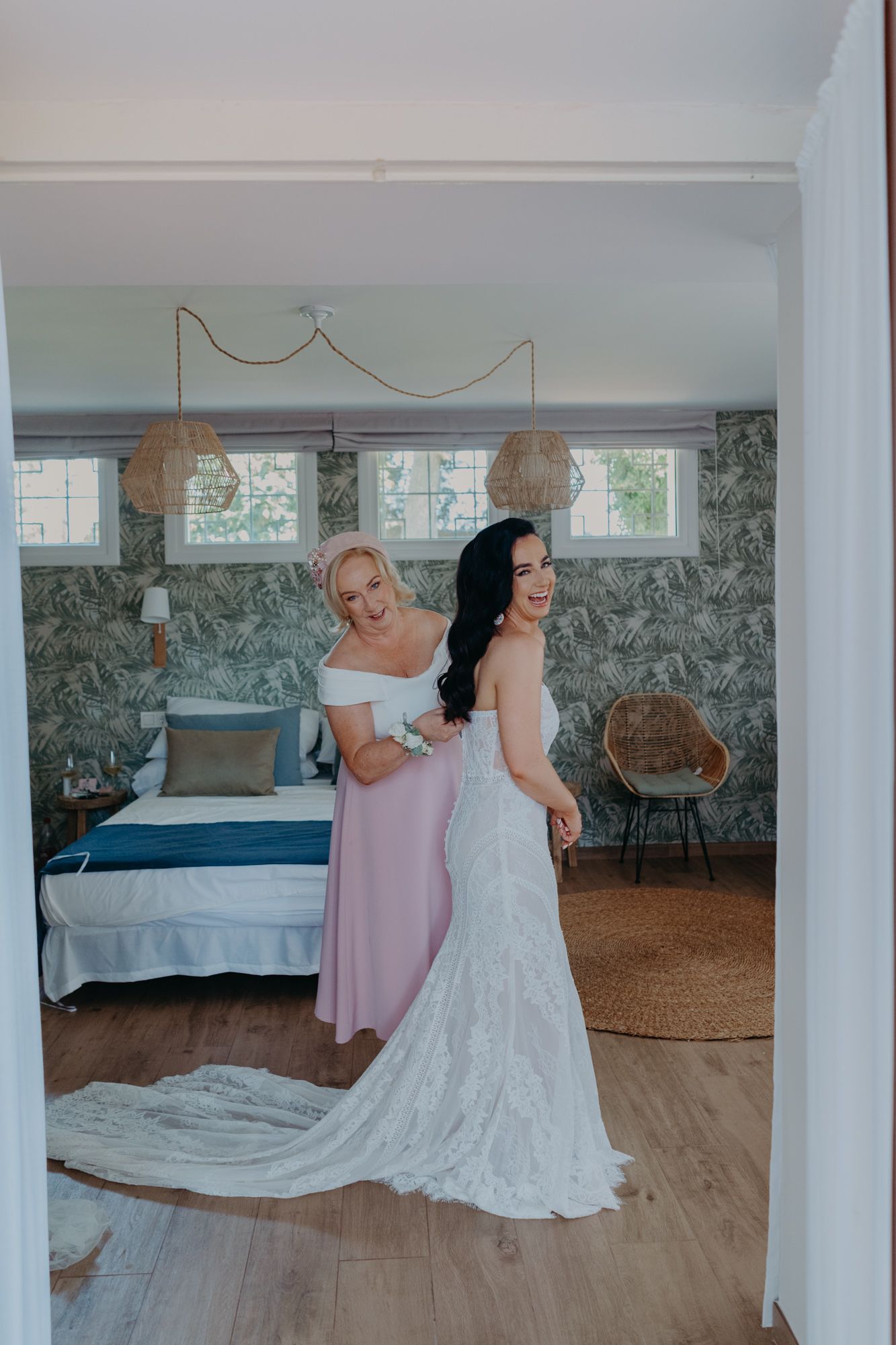 A wedding dress reveal moment captured in a stylish bedroom with gray wallpaper and natural lighting.