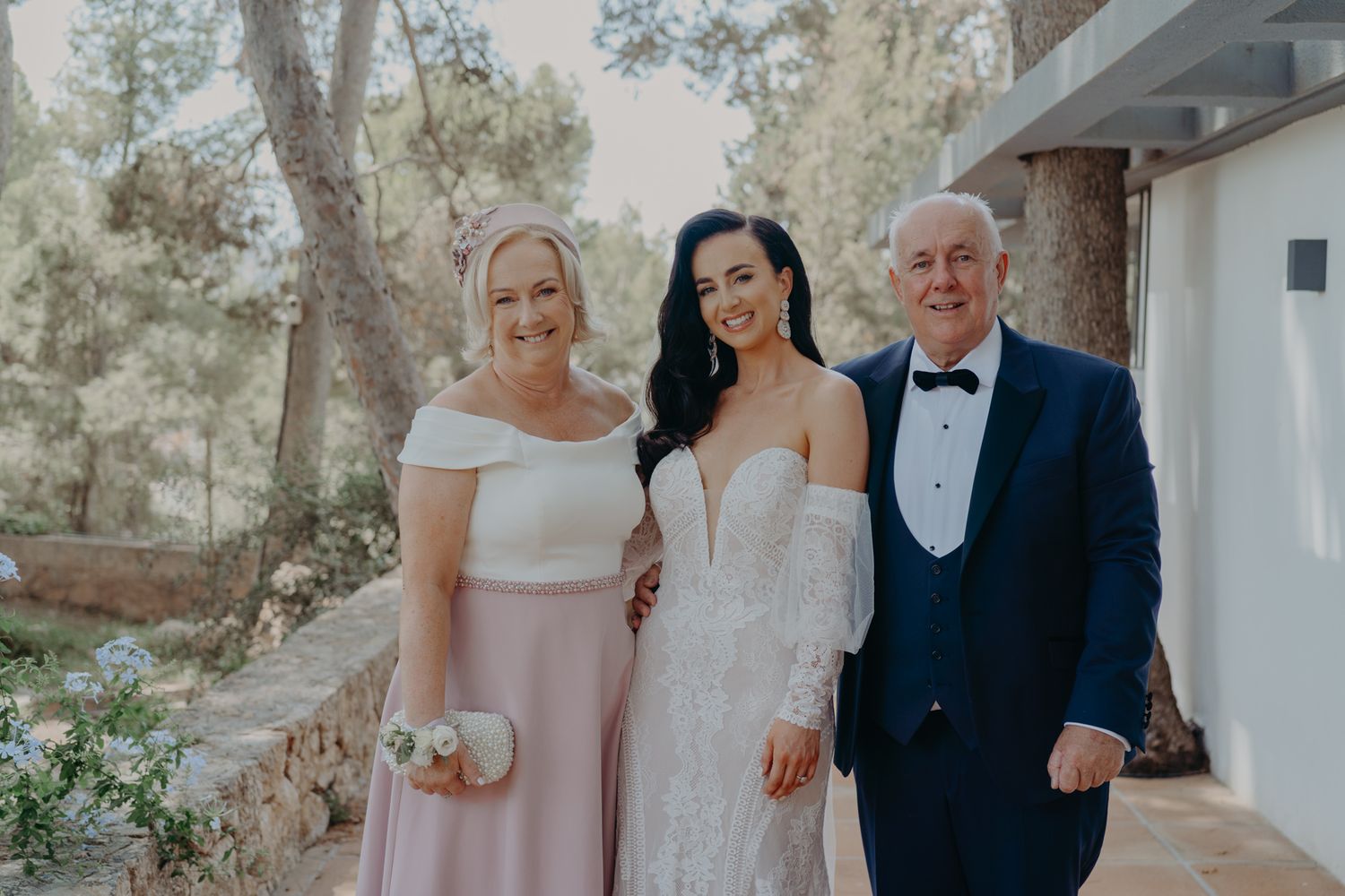 Outdoor wedding portrait taken against natural wooded background with elegant formal attire.
