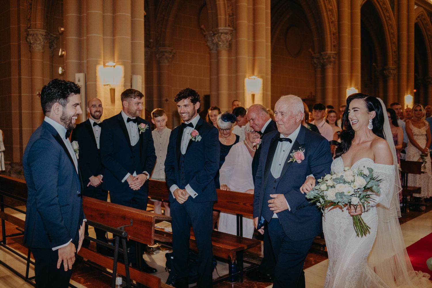Wedding ceremony guests gather in the pews of a grand cathedral.