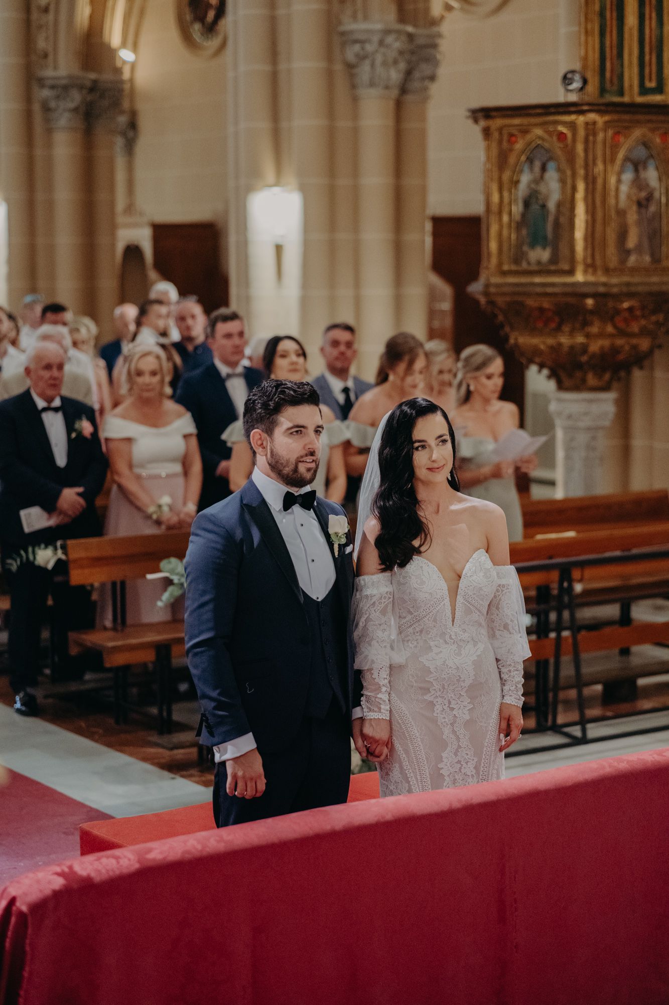 Traditional church wedding ceremony in an ornate cathedral with decorative altar and columns.