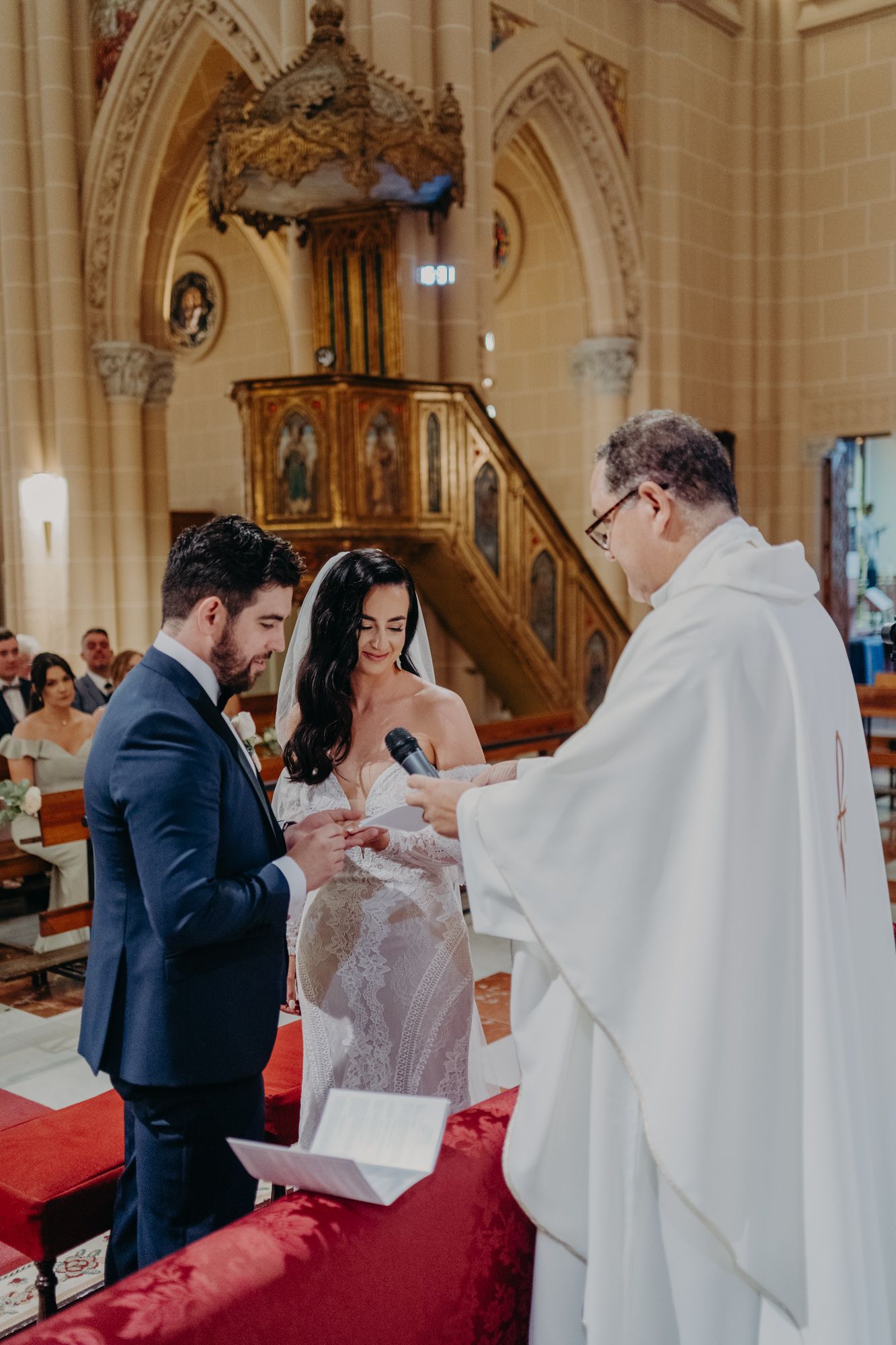 Wedding ceremony taking place inside a historic church with ornate wooden pulpit and gothic arches.