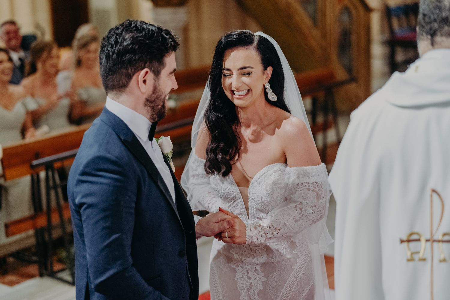 Joyful exchange of wedding rings during Catholic church ceremony.