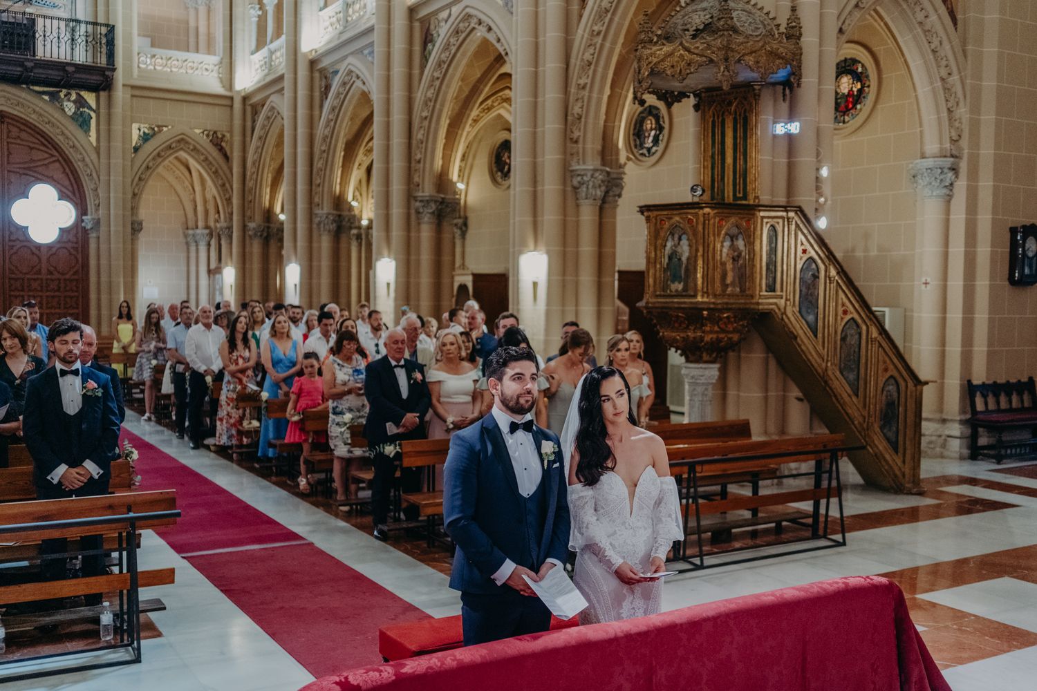 A wedding ceremony in a beautiful cathedral with high vaulted ceilings and ornate architectural details.