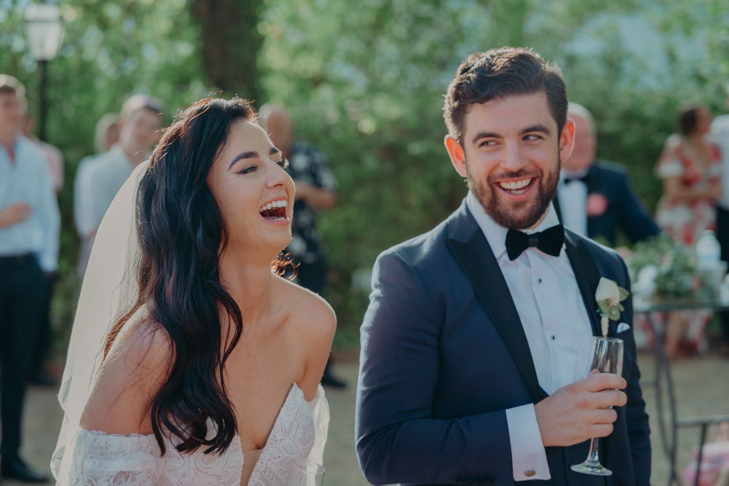 Candid moment of laughter during outdoor wedding reception.