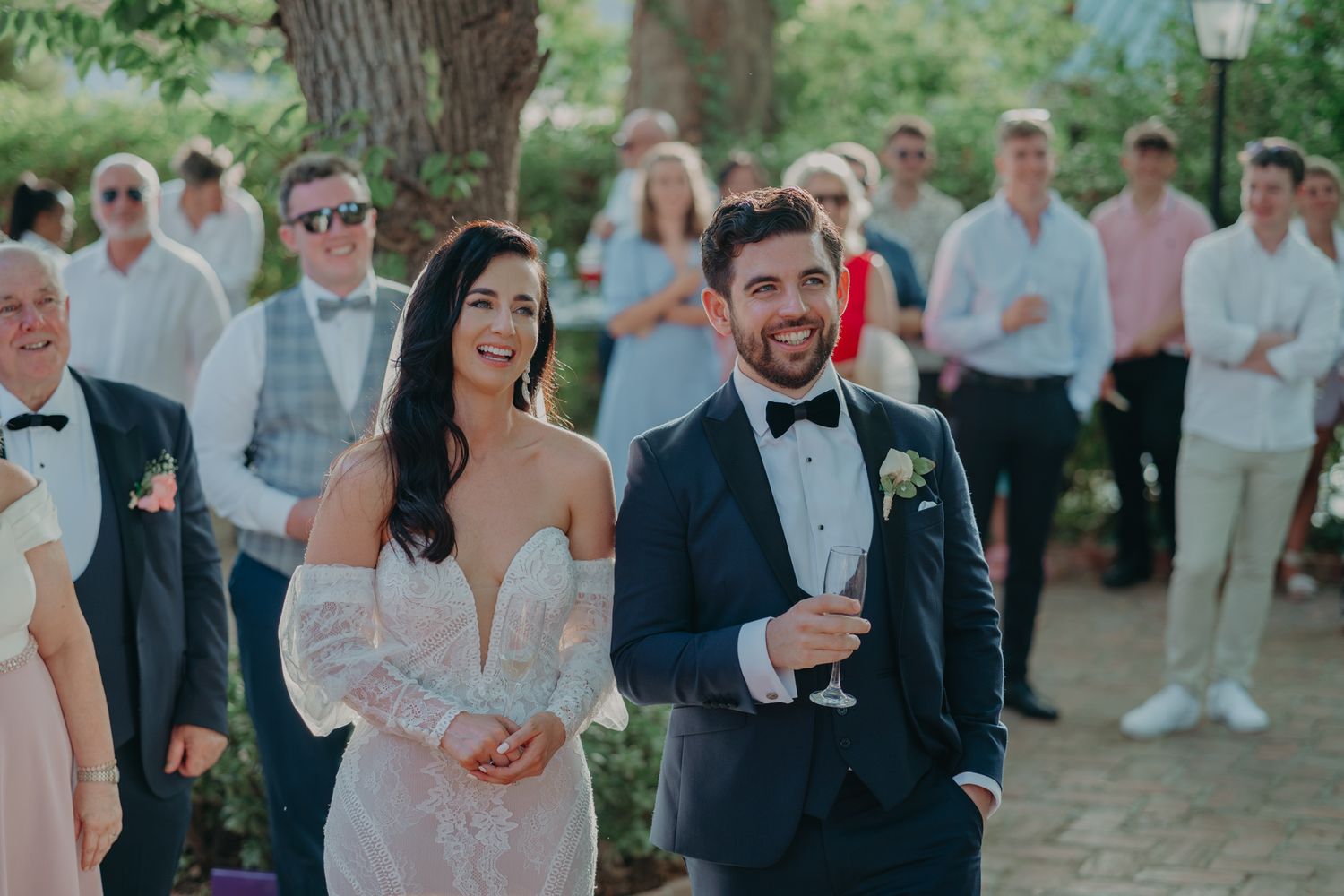 Elegant wedding couple walking outdoors surrounded by guests at a garden ceremony.