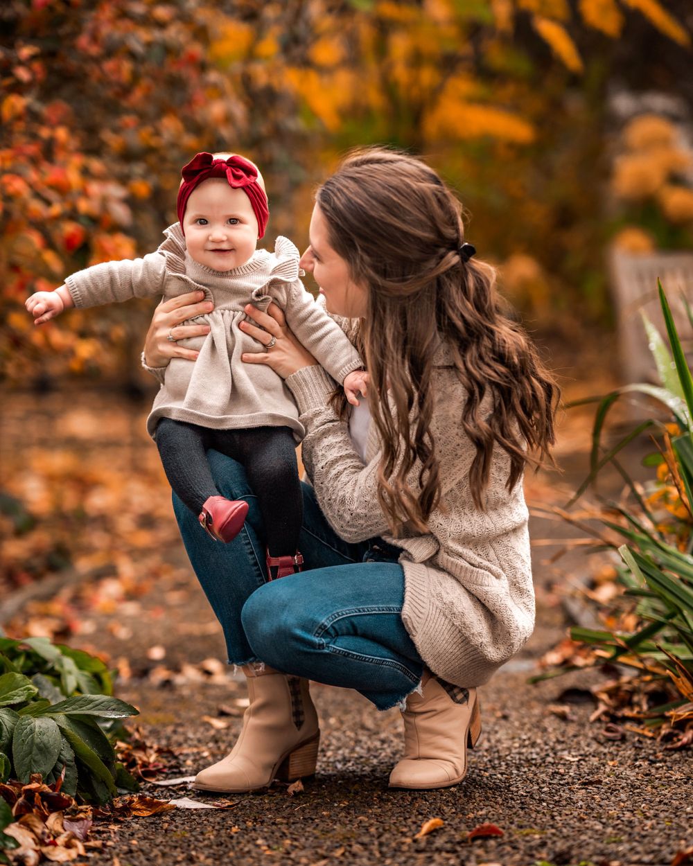 A sweet autumn moment captured between two people wearing matching beige sweaters among fallen orange leaves.