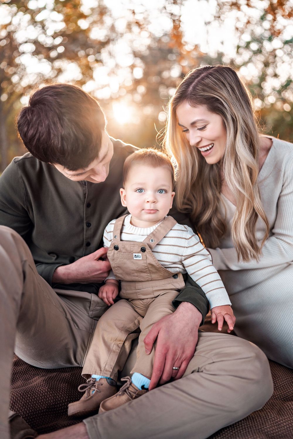 Family shares a tender moment together outdoors during golden hour sunset in autumn setting.