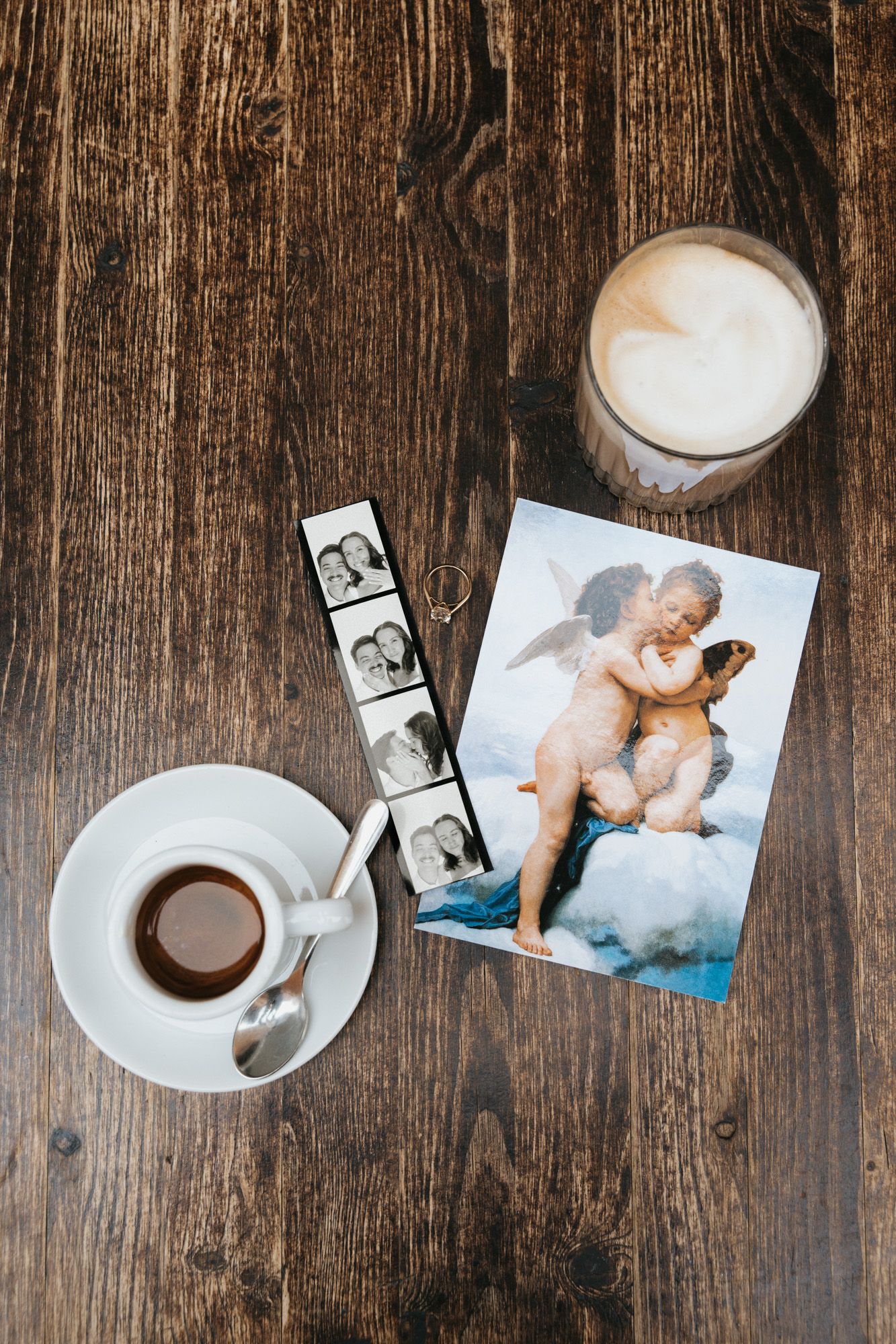 A cup of coffee and glass of milk on rustic wooden table with photos and film strip.