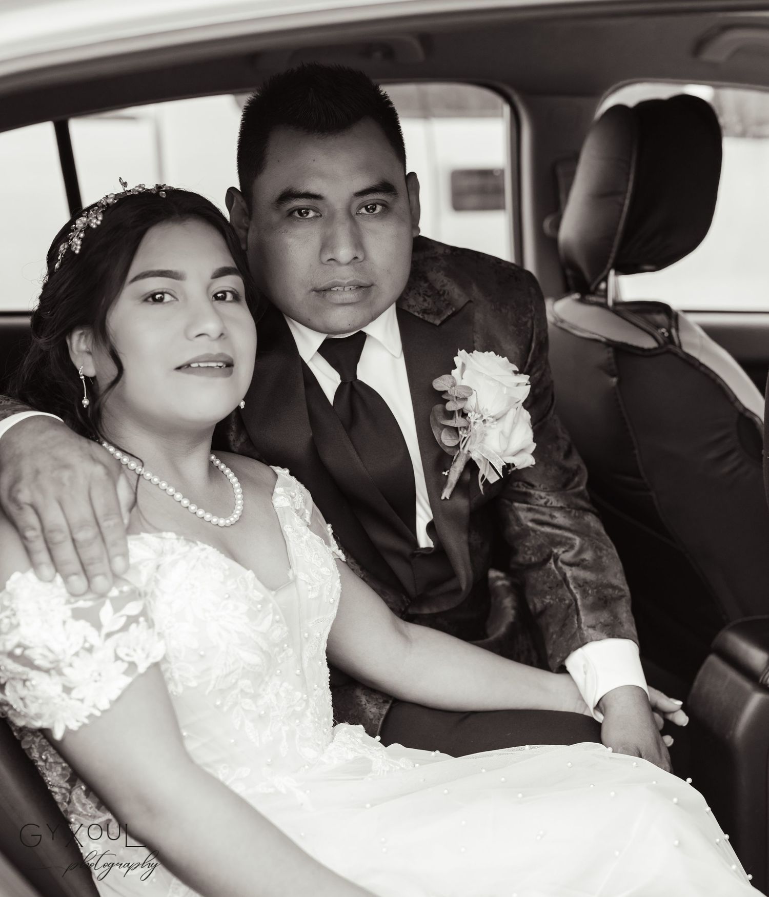Vintage style wedding portrait of couple seated together in car.