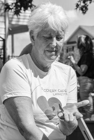 A person in a white Discovery Cafe Lafayette t-shirt sits outdoors, shown in black and white photography.