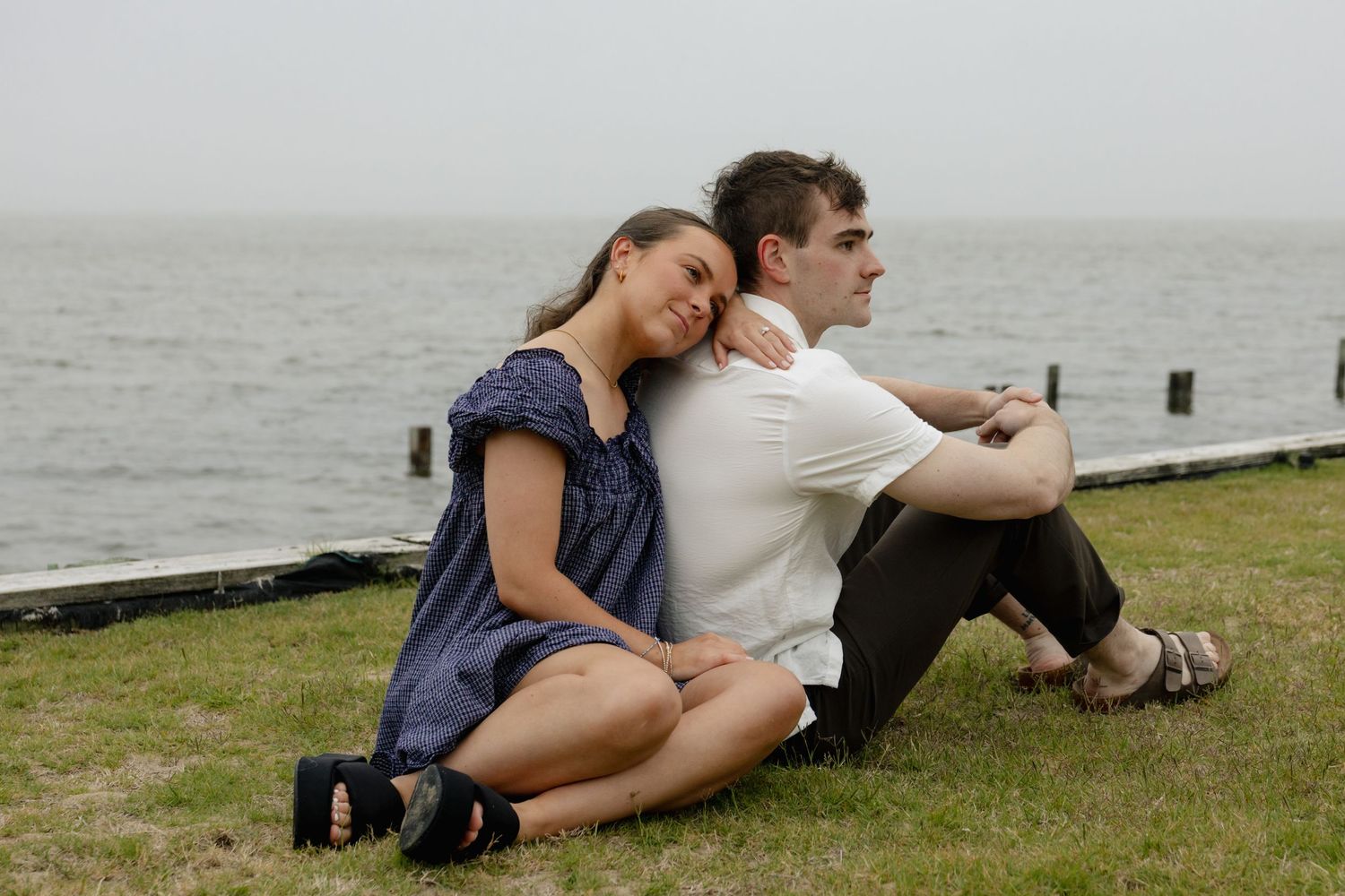Romantic couple embracing on beach in white clothing during sunset photoshoot.