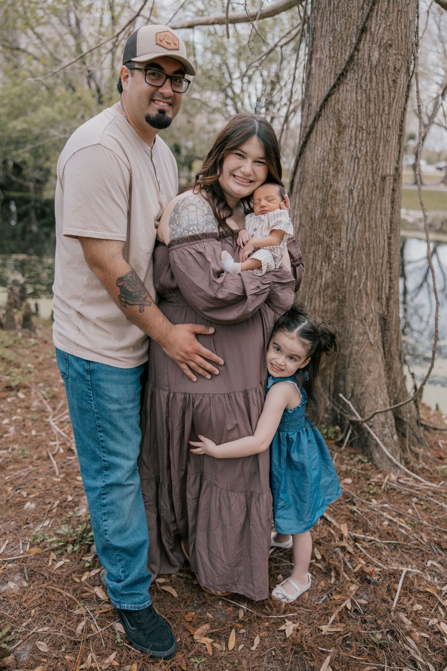 Family poses together near a tree during an outdoor photo session in casual attire at Lake Parker Park