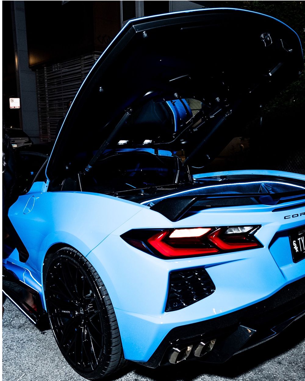 Light blue Corvette sports car exterior details and rear lights shown at night.