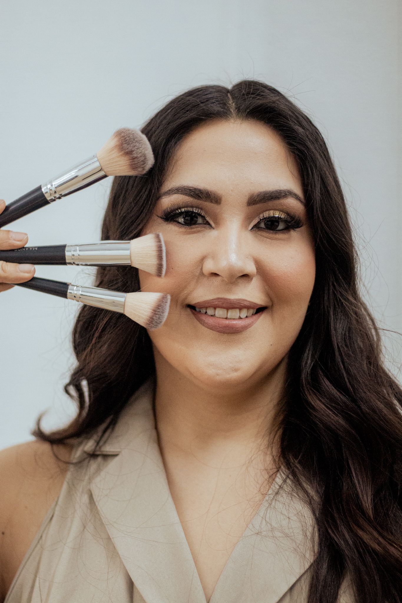 Professional makeup brushes held against the cheek showing beauty tools during cosmetic application.