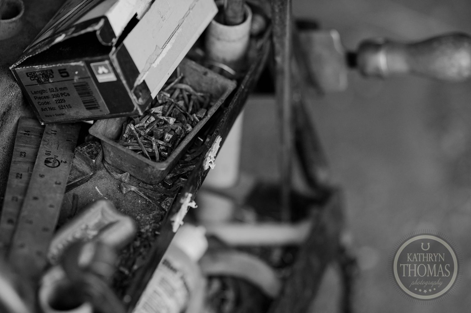Close-up black and white shot of tools and hardware in a farrier cart.