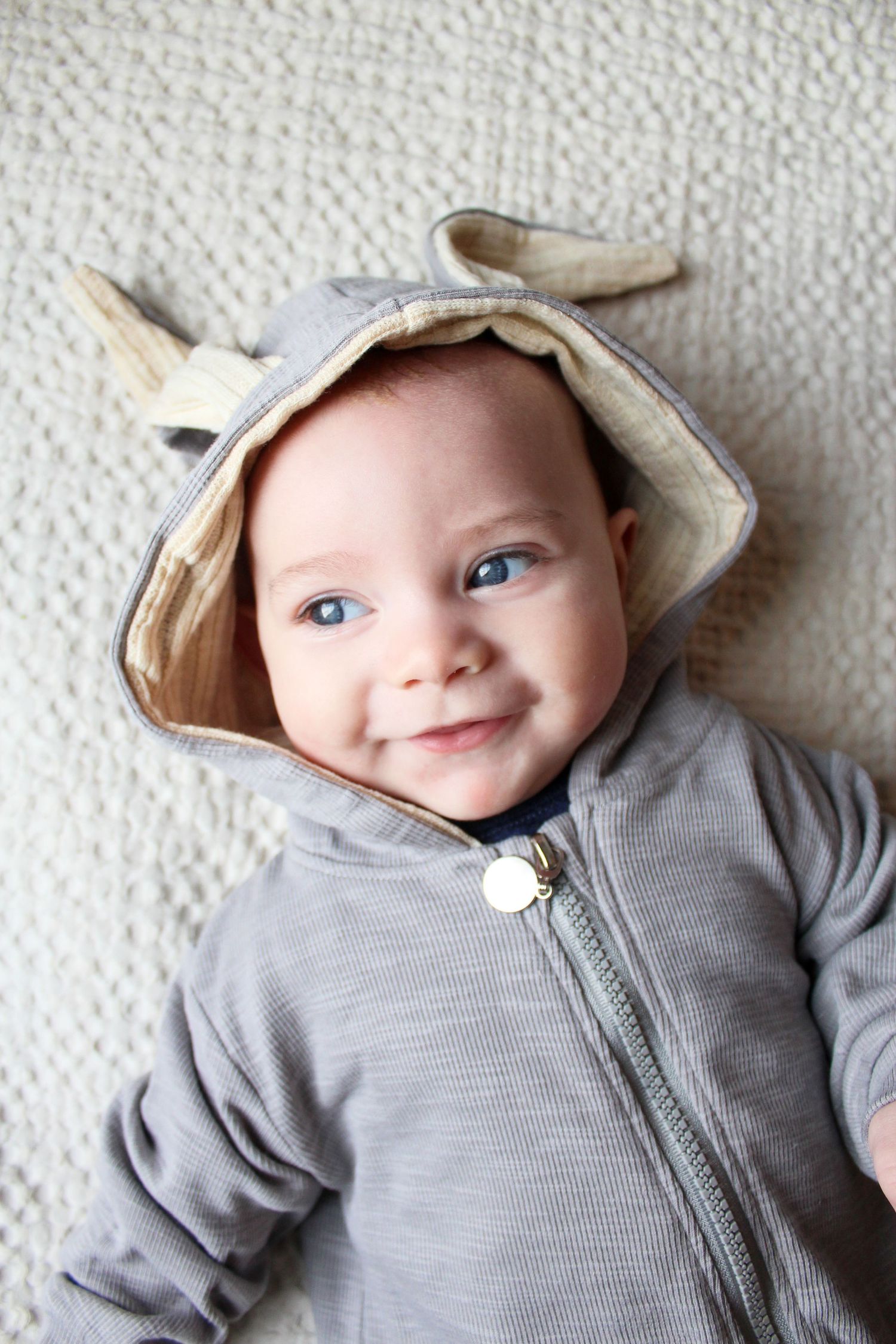 Springfield, IL family photographer captures baby laying down and smiling in a bunny onesie for easter photos