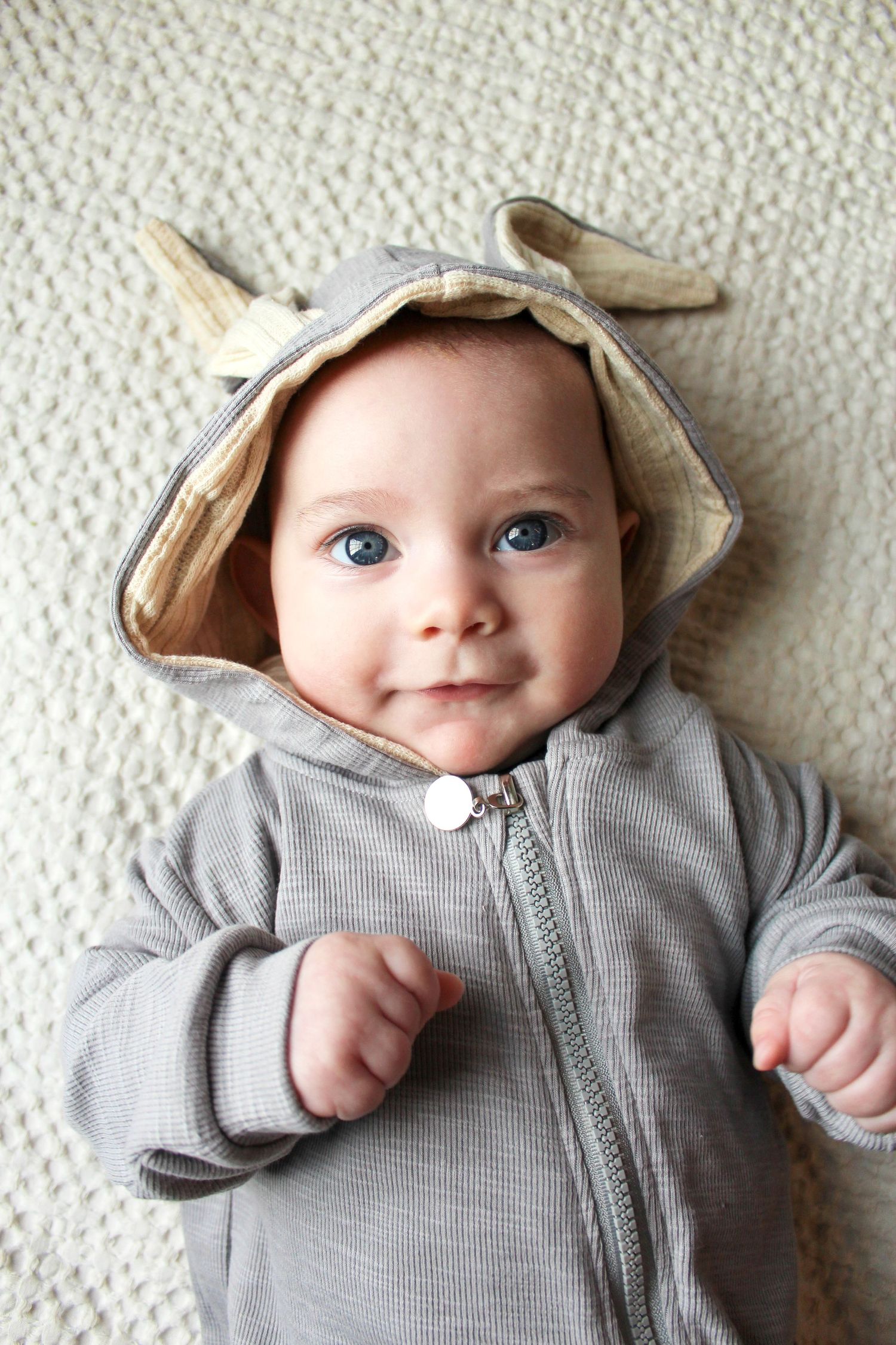 Springfield, IL family photographer captures baby laying down and smiling in a bunny onesie for easter photos