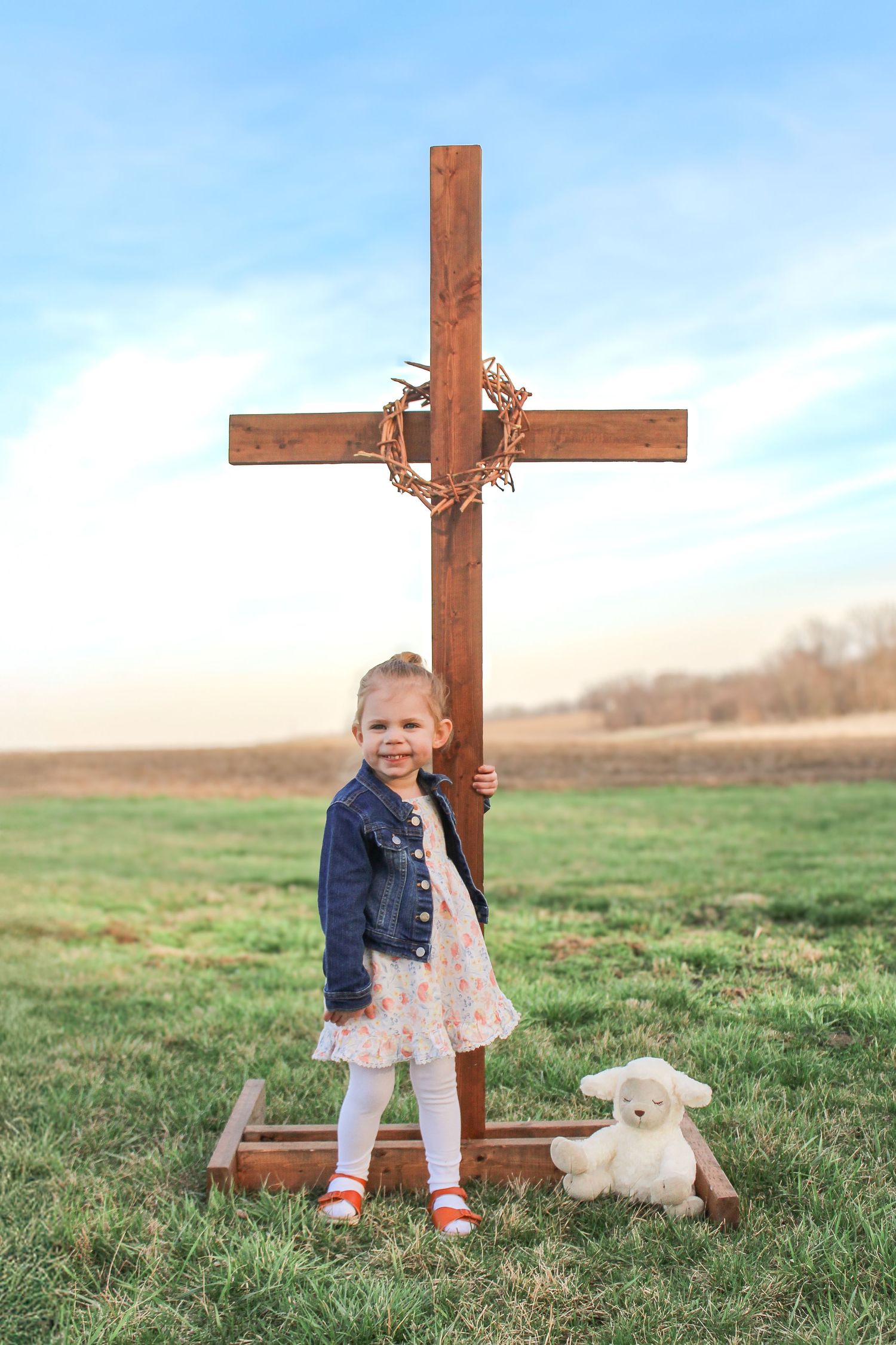 Springfield, IL photographer captures a young girl smiling in front of a cross with thorns in front of the countryside