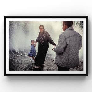 People enjoying a misty moment near a water feature in a black and white framed photograph.