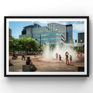 People cooling off at an urban water fountain plaza with modern buildings in the background.