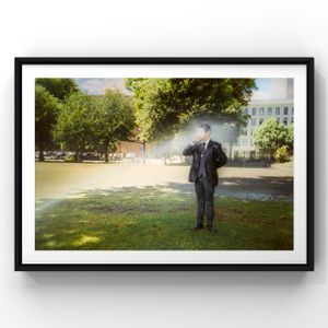 Suited figure stands alone in sunlit park with mist and trees in background.