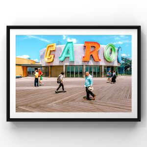 Colorful retro CARO sign with people walking on a wooden boardwalk under bright blue sky.