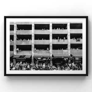 Black and white photograph of crowds gathering on multiple levels of a parking structure or building.